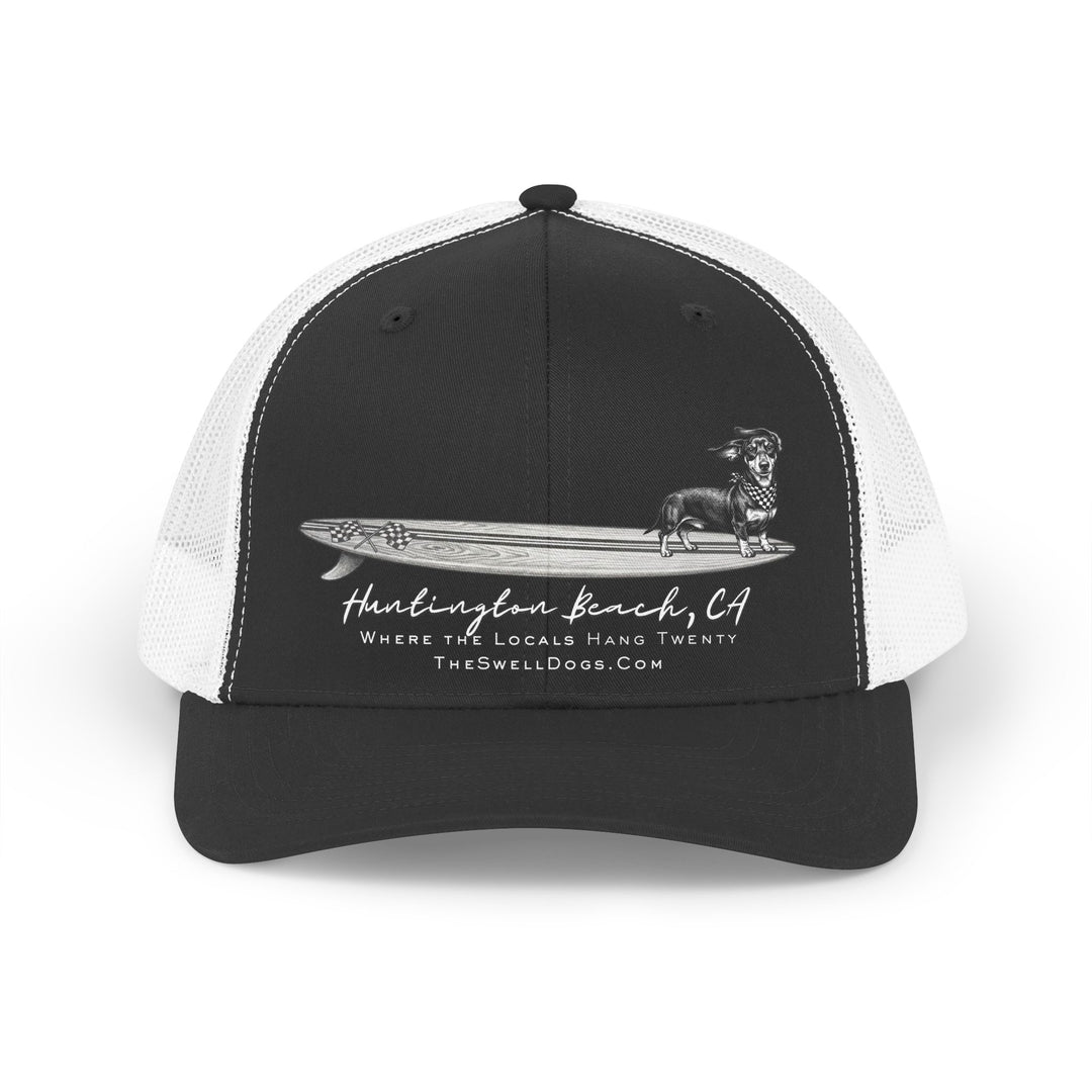 Trucker hat featuring a Dachshund dog standing on a surfboard with "Huntington Beach, CA" text