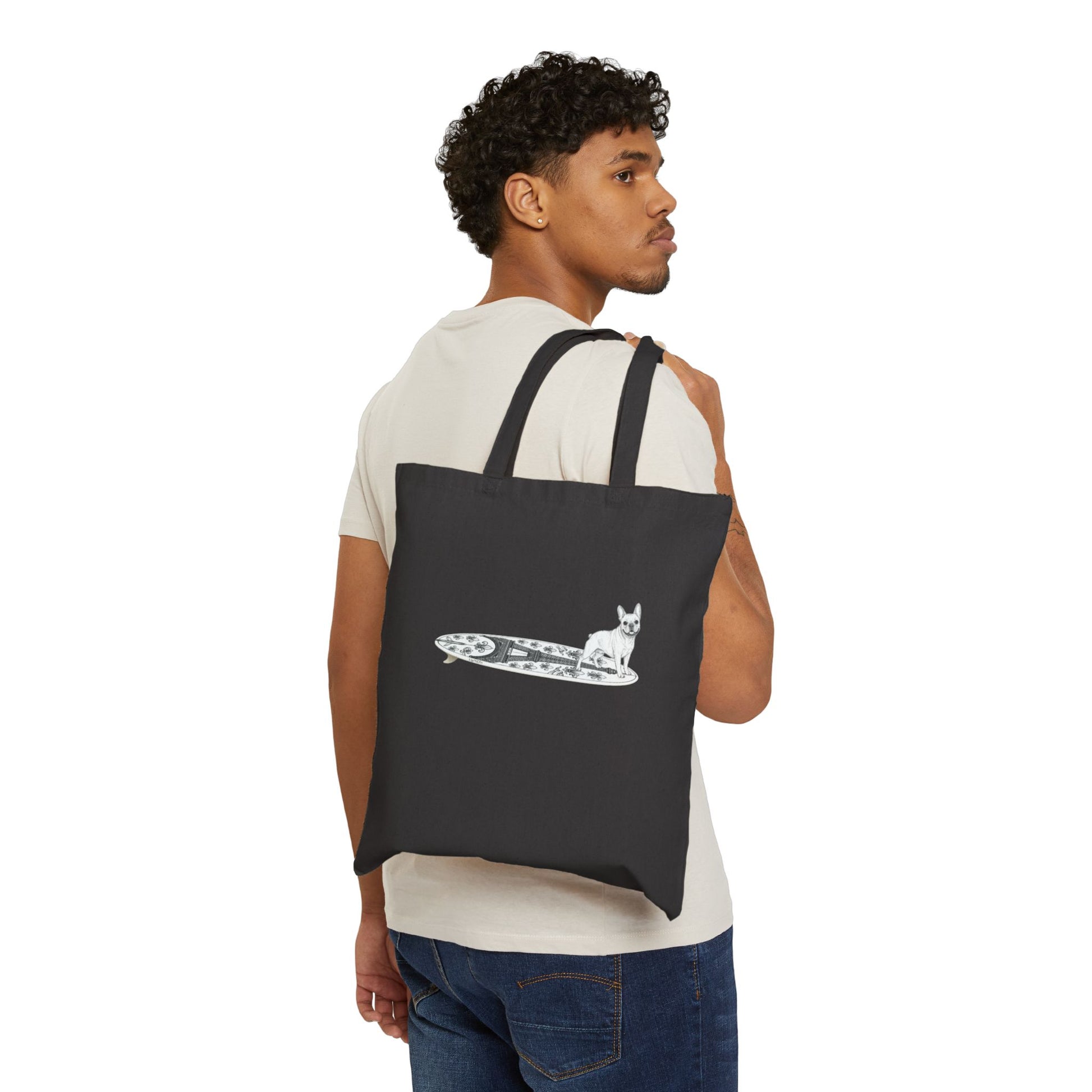 Man carrying a black  tote bag with a French Bulldog on an Eiffel Tower surfboard.