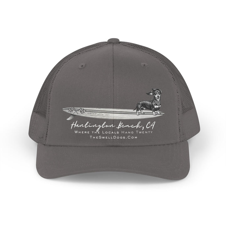 Grey trucker hat featuring a Dachshund dog standing on a surfboard with "Huntington Beach, CA" text