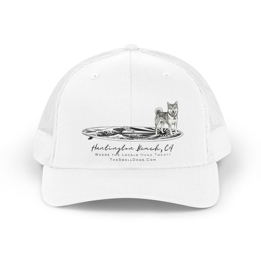 White trucker hat featuring a Shiba Inu dog standing on a Japanese surfboard with "Huntington Beach, CA" text