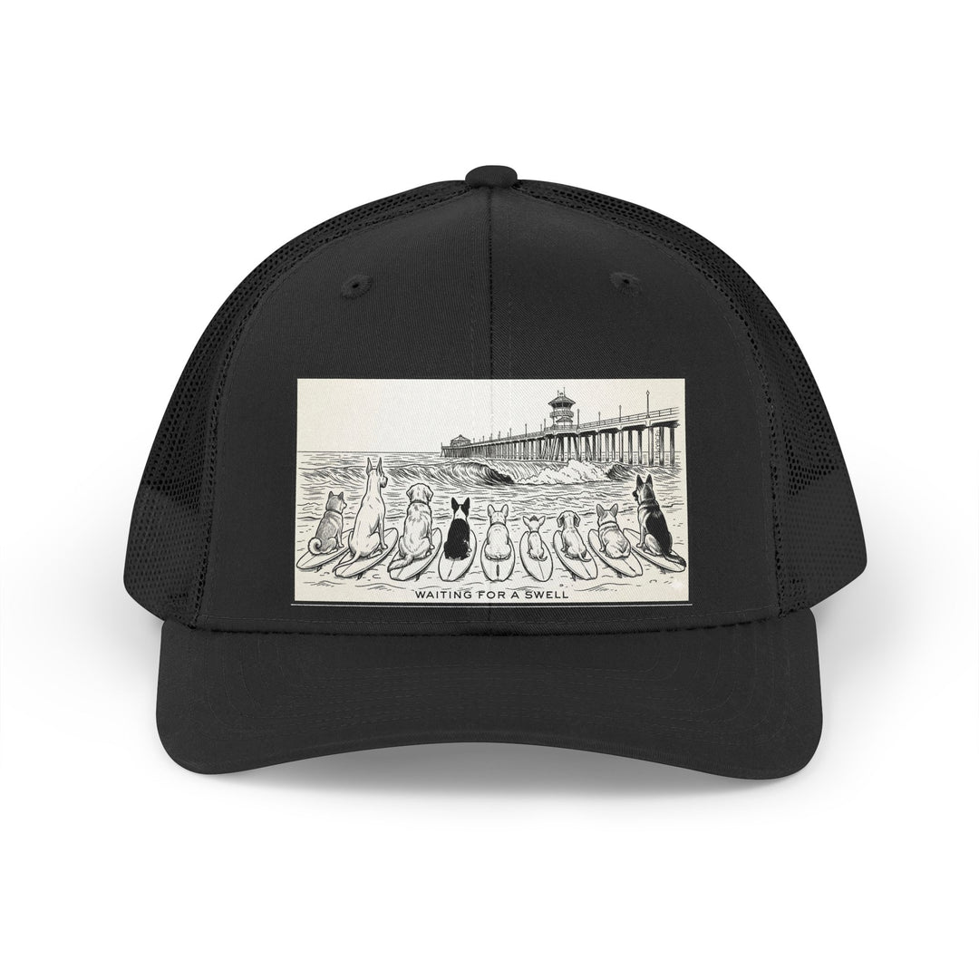 Black trucker hat with a picture of a pack of nine dogs sitting on their surfboards, facing the ocean, with the Huntington Beach pier in the background. It says Waiting for a Swell at the bottom.