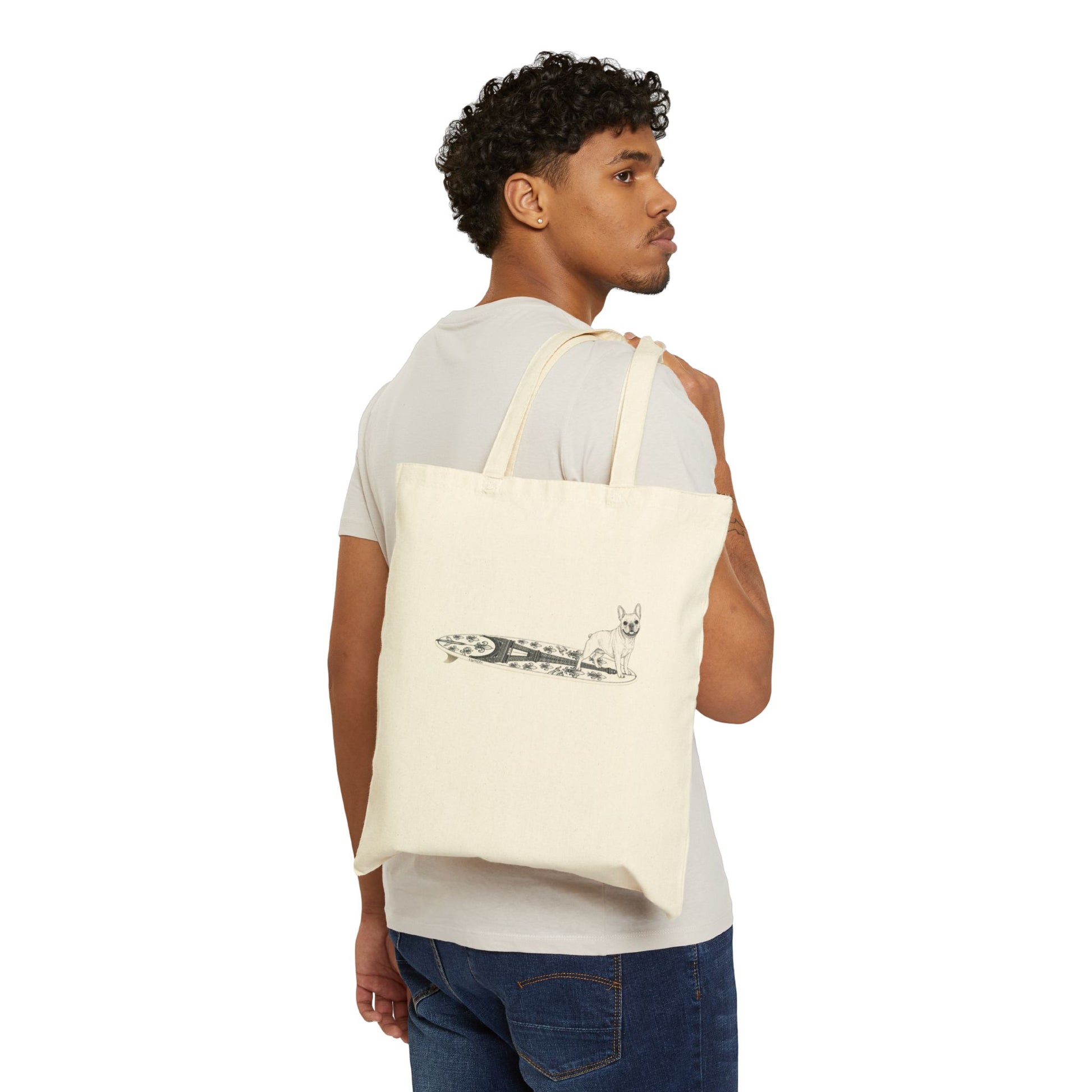 Man carrying a Beige tote bag with a French Bulldog on an Eiffel Tower surfboard.