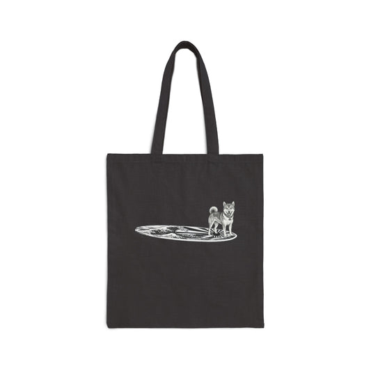 Black tote bag with a Shiba Inu dog on a surfboard with a graphic of a Japanese wave and sun flag on it.