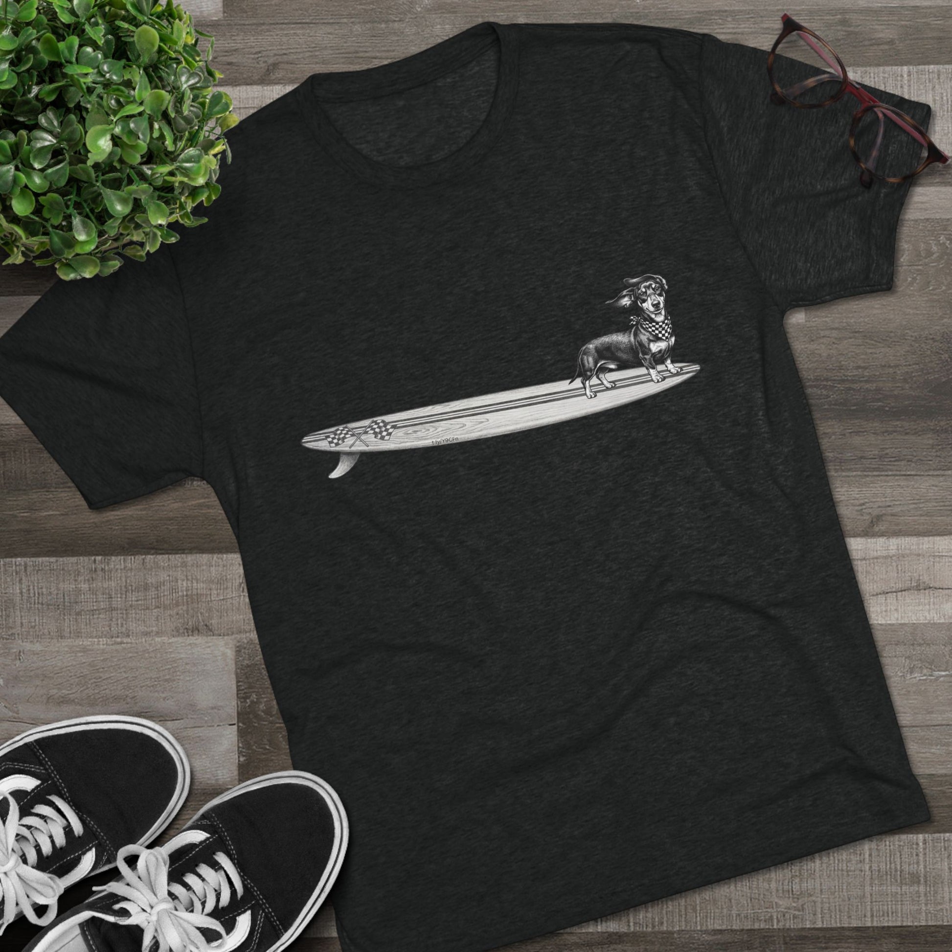 Black Dachshund surf t-shirt with checkered racing flag bandana and wood grain surfboard design styled on wood floor with Vans sneakers — The Swell Dogs