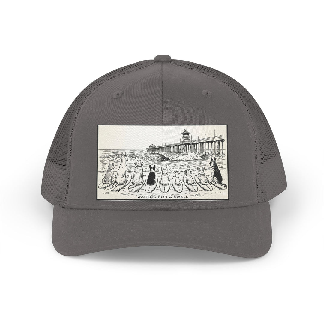 Gray trucker hat with a picture of a pack of nine dogs sitting on their surfboards, facing the ocean, with the Huntington Beach pier in the background. It says Waiting for a Swell at the bottom.