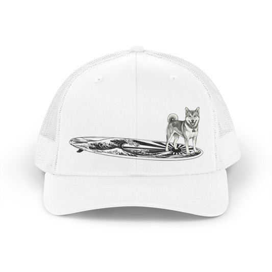 White truckers hat with a Shiba Inu dog on a surfboard with a graphic of a Japanese wave and sun flag on it.