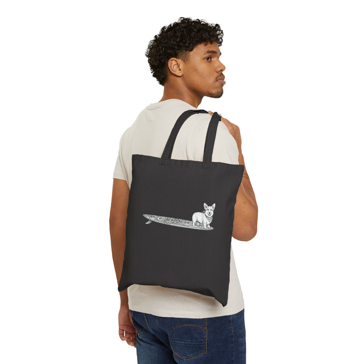 Man carrying black Corgi surf tote bag with hibiscus bandana tiki surfboard design over shoulder — The Swell Dogs