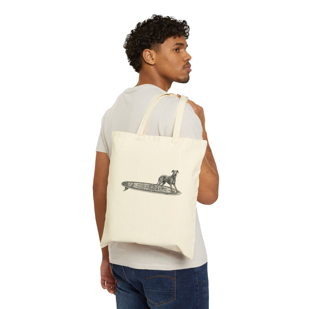 Man carrying a beige  tote bag with a Great Dane on a longboard with wild boar crests and suns on it.
