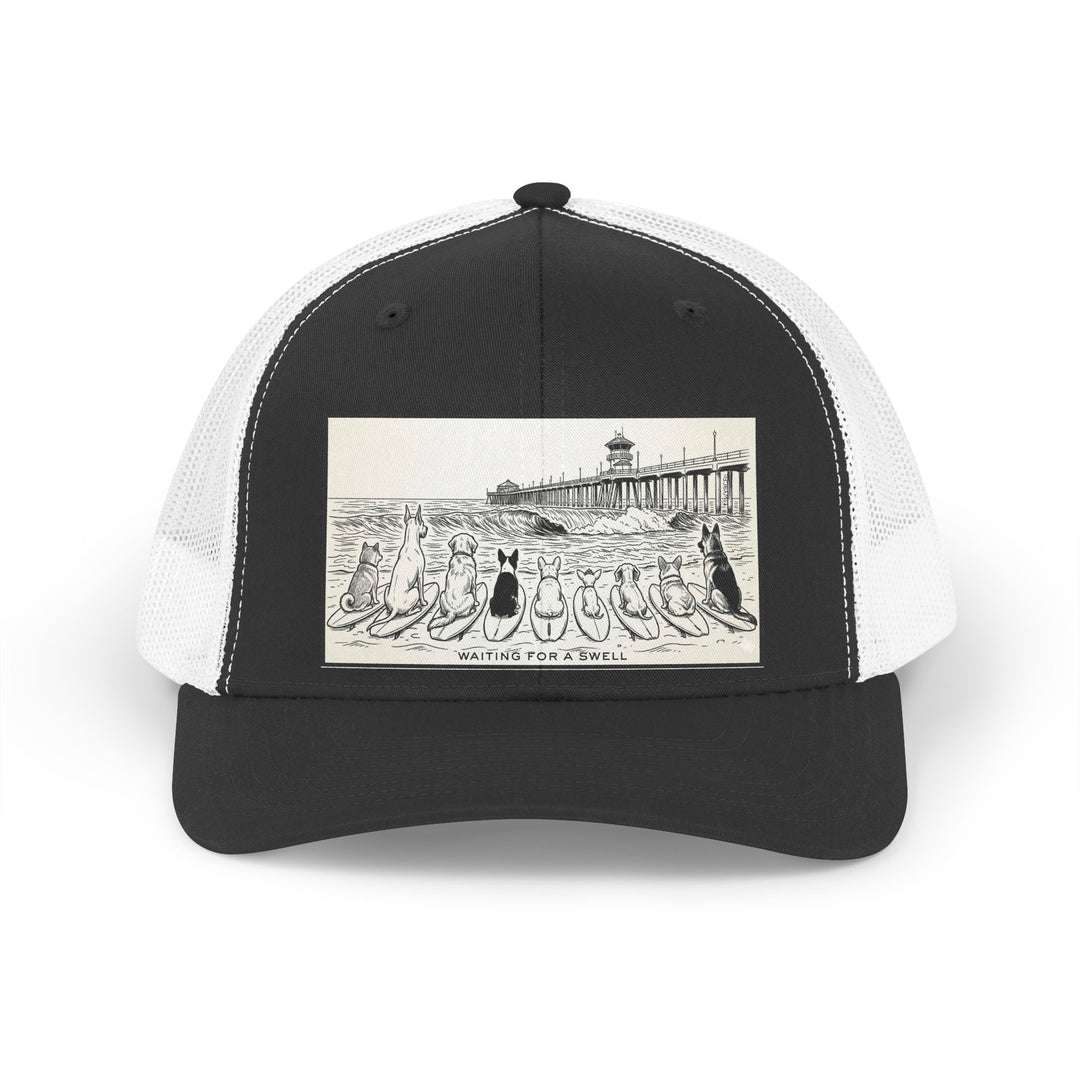 Black and white trucker hat with a picture of a pack of nine dogs sitting on their surfboards, facing the ocean, with the Huntington Beach pier in the background. It says Waiting for a Swell at the bottom.