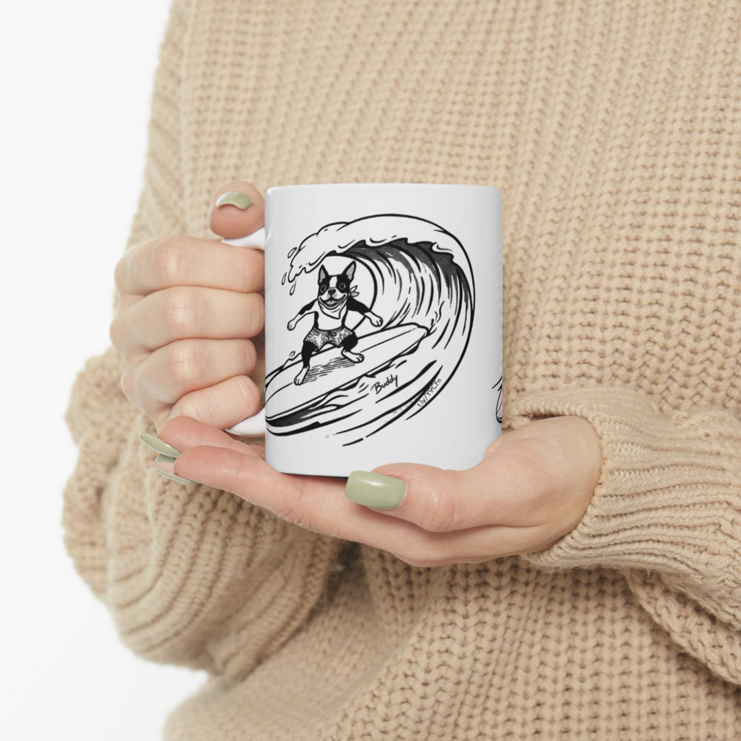 White mug with a black and white graphic of a Boston Terrier surfing on a big wave with a white background.