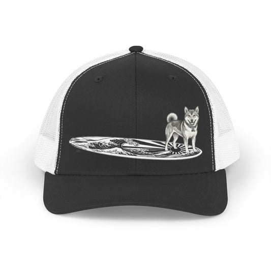 Black and white truckers hat with a Shiba Inu dog on a surfboard with a graphic of a Japanese wave and sun flag on it.