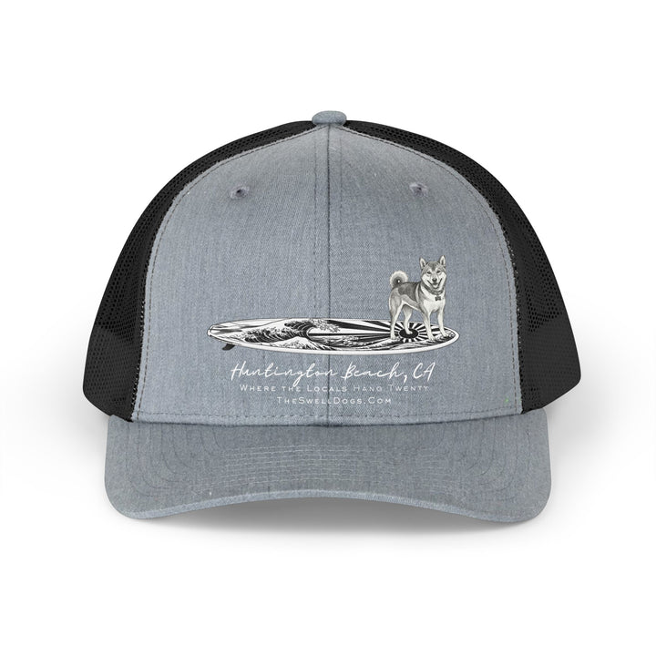 Grey trucker hat featuring a Shiba Inu dog standing on a Japanese surfboard with "Huntington Beach, CA" text