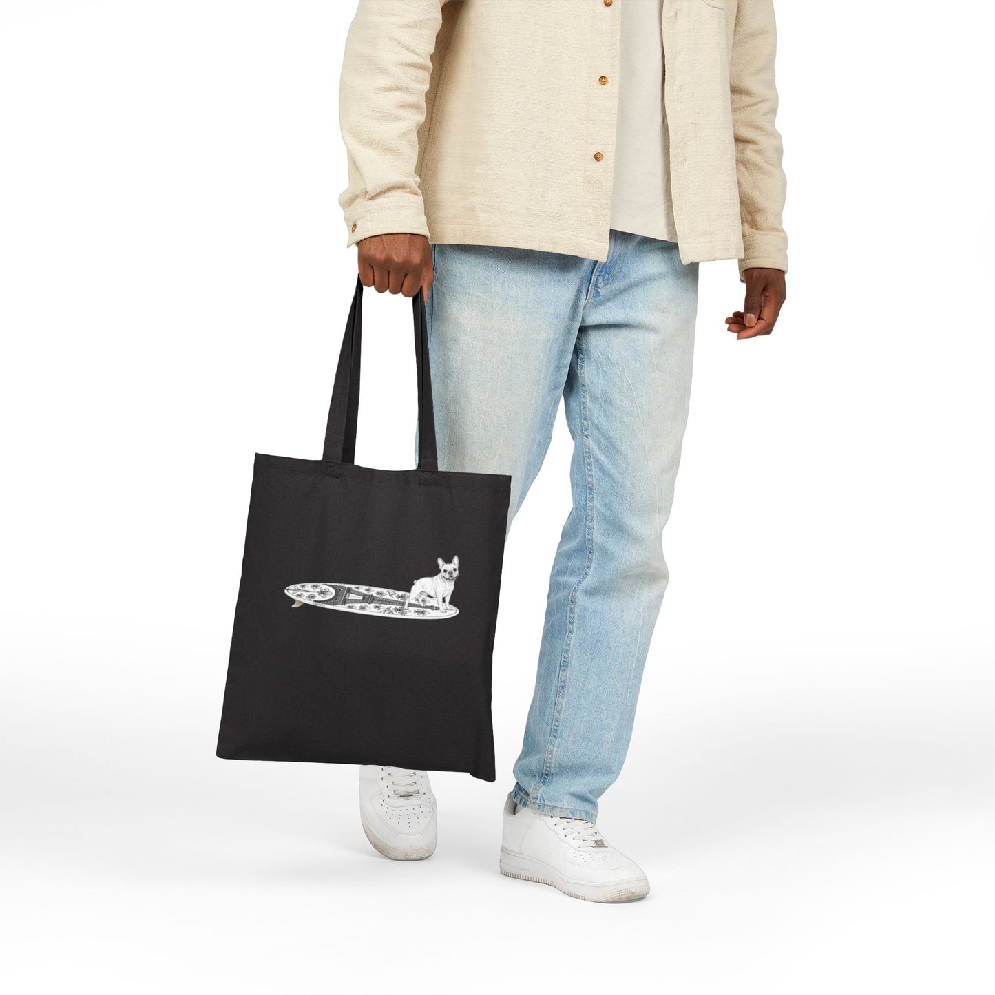 Person holding a black tote bag with a French Bulldog on an Eiffel Tower surfboard.