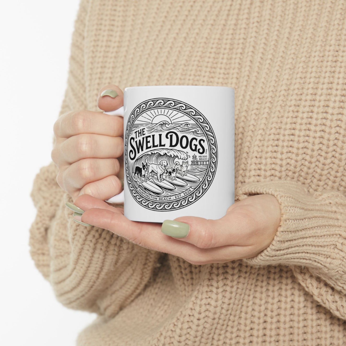 Woman holding a White mug with The Swell Dogs logo on it.