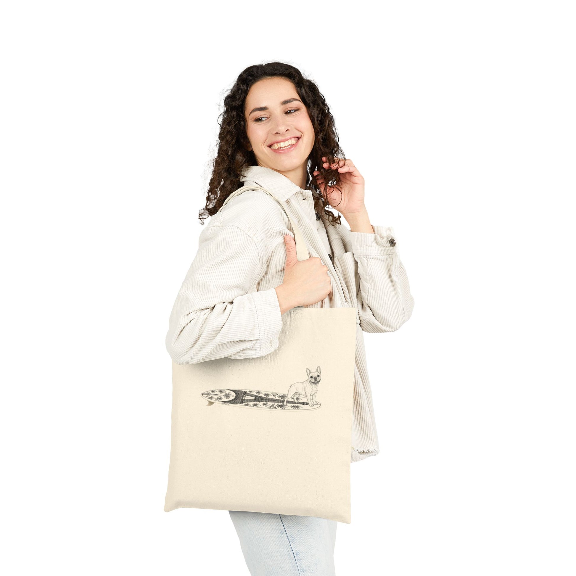 Woman holding a Beige tote bag with a French Bulldog on an Eiffel Tower surfboard.